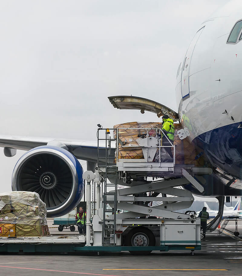 Wide-body cargo aircraft being loaded with air freight pallets on the tarmac